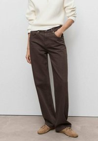 Brown wide-leg jeans made from cotton blend fabric, featuring a five-pocket design and stitched detailing, paired with beige footwear.