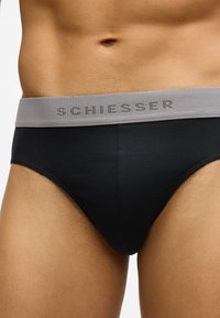 Fekete férfi alsónadrágok puha anyagból. Szürke derékpánton "SCHIESSER" felirattal kontrasztos színben. Simaságú textúra.