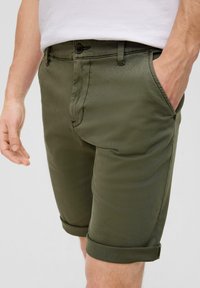 Olijfgroene katoenen shorts met een gladde textuur, slim fit, omgeslagen zoom en een knoopsluiting aan de voorkant. Zakjes aan beide zijden.