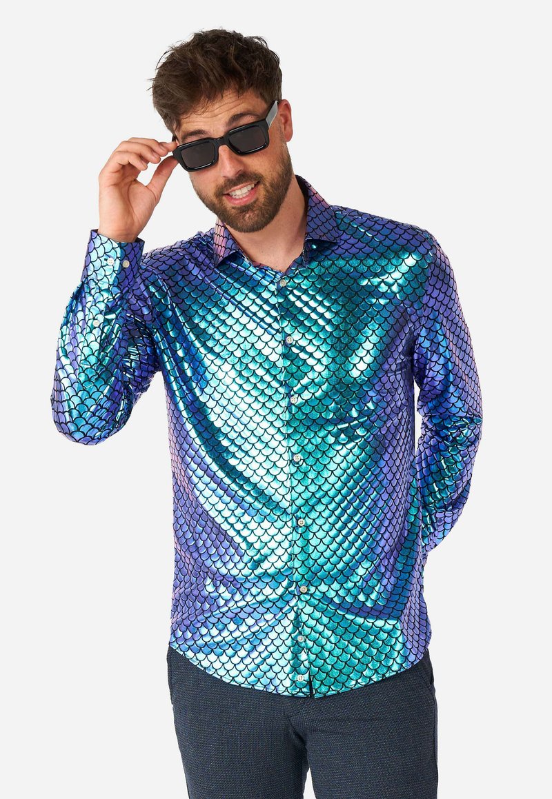 Camicia lucida e iridescente con bottoni, caratterizzata da un motivo a scaglie nei toni del blu e del verde, con colletto e maniche lunghe. Indossati occhiali da sole neri.
