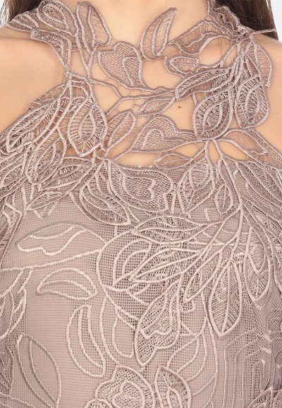 Top in pizzo con ricami floreali color taupe, dotato di scollatura alta e dettagli a taglio, che mettono in mostra intricati motivi a foglia e texture.