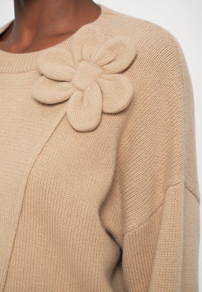 Pulover bej din tricot, cu o aplicație texturată de floare supradimensionată pe umăr, având guler ribbed și un material moale, confortabil.