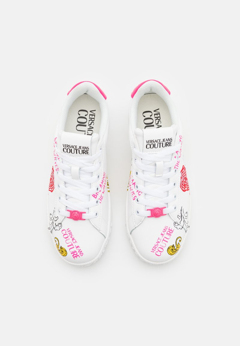 Sneakers bianchi di Versace Jeans Couture con accenti rosa, testo decorativo, illustrazioni floreali e in stile barocco, visti dall'alto su uno sfondo bianco.