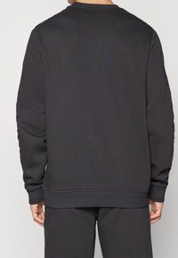 Tmavě šedá mikina vyrobená z měkké tkaniny, s kulatým výstřihem, dlouhými rukávy a žebrovanými manžetami a spodním lemem pro pevné uchycení.