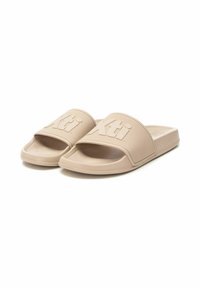 Sandalias de goma beige tipo slide con una correa texturizada que presenta el logo elevado "Xti", diseño de punta abierta y suela plana. Ligeras y casuales.