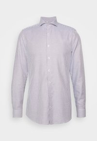 Chemise à carreaux blancs et bleu marine à manches longues avec un col boutonné, présentant un tissu texturé et une fermeture  à boutons sur le devant.