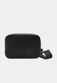 Black rectangular bag made of smooth leather, featuring a zip closure and a removable strap. Simple design with clean edges and minimal detailing.