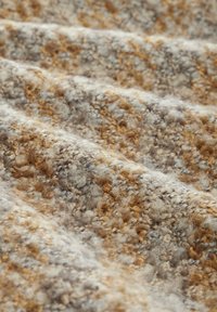 Tekstil med en tekstureret overflade i beige, grå og brune nuancer. Har en blød, fnugget sammensætning med varierede løkkehøjder og mønstre.