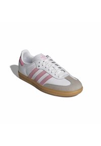 Vit sneaker med rosa accenter och tre ränder, med en tåhätta i mocka, gummisula och texturerad läderöverdel.
