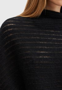Indumento in maglia nera e dalle texture, con strisce orizzontali, dotato di un collo alto e realizzato in un tessuto morbido e leggermente traslucido. I dettagli includono variazioni di spessore.