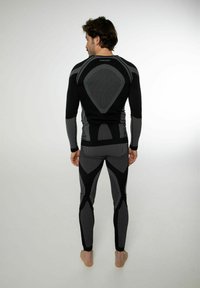 Maglietta termica a maniche lunghe nera e grigia e leggings con un motivo geometrico, texture a coste e design aderente per l'abbigliamento sportivo.