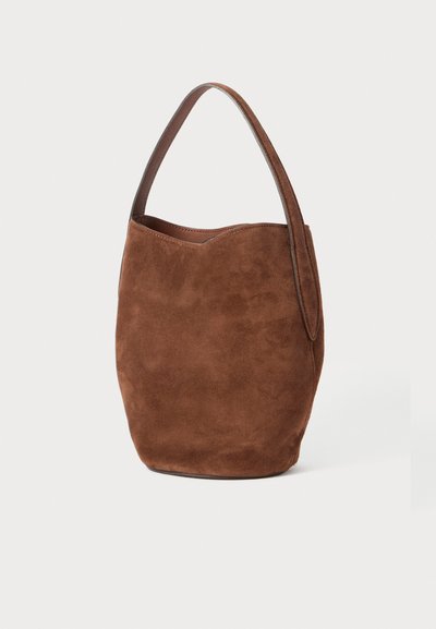 Smeđa suede torba s zakrivljenim vrhom, jednim remenom za rame i mekim teksturama. Minimalističkog oblika, pogodna za svakodnevnu upotrebu.