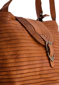 Sac à main en cuir tan avec une texture cousue et nervurée, doté d'une fermeture à rabat et de détails en boucle métallique. Deux bandoulières robustes.