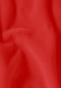 Tissu rouge avec une texture douce et duveteuse, présentant des plis visibles qui créent des ombres et des reflets délicats.