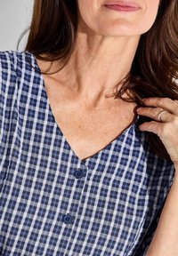 Abito a scacchi Navy e bianco con scollatura a V, maniche corte e due bottoni scuri davanti. Tessuto morbido e testurizzato.