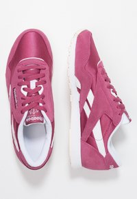 Růžové tenisky s kombinací semiše a síťoviny, bílými akcenty, kulatou špičkou a šněrováním. Logo po straně.