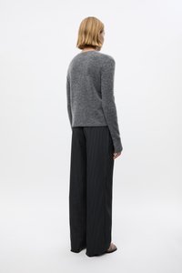Gray wool sweater with a round neck, fitted sleeves, paired with black pinstriped wide-leg trousers. Background is plain white.