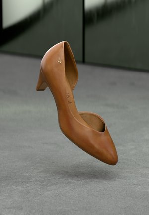 Leren hoge hakken in bruin met een spitse neus en een uitgesneden ontwerp. Voorzien van een kleine gouden accent vlakbij de hak.