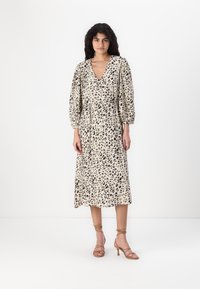 Käärmeennahkakuosiset mekko, jossa on syvä V-pääntie, puffattuja hihoja ja kireä vyötärö. Mekko ulottuu polvitaipeeseen asti, on kevyttä kangasta ja siinä on hienovarainen pinta.