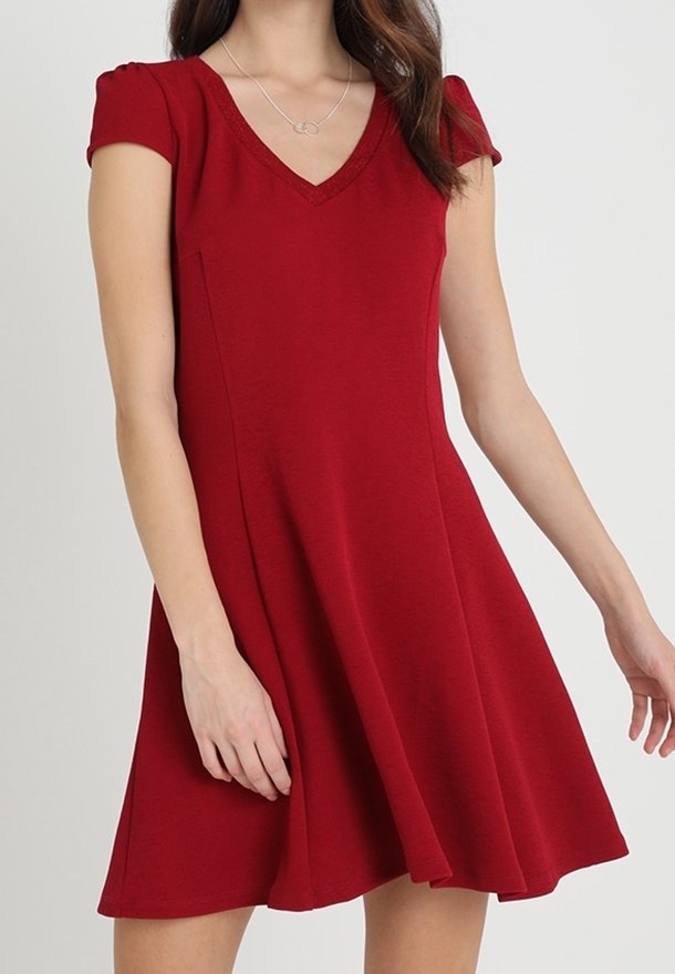 Vestido rojo de manga corta con escote en V. Falda acampanada y tejido suave. Presenta pliegues sutiles en las mangas y un diseño simple y clásico.