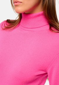 Helles pinkes Rollkragenpullover aus einem weichen, feinen Strickstoff mit geripptem Kragen und Bündchen, der eine taillierte Silhouette und eine glatte Textur aufweist.