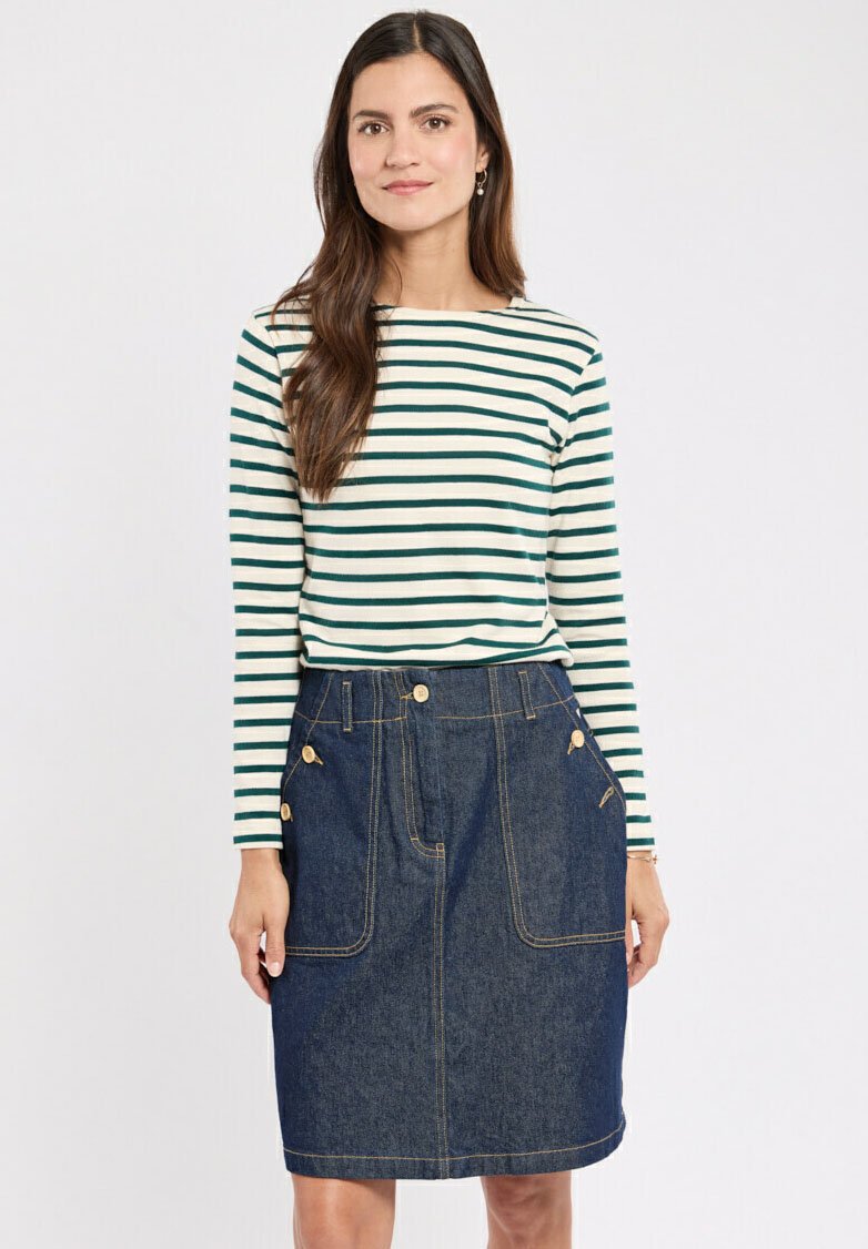 Gestreepte langearmige top in wit en donker groen, gecombineerd met een donkere spijkerrok met gouden knopen en grote voorzakken.