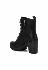 Botines de cuero negro con un tacón alto texturizado, detalle de cordones y cremallera lateral; suela robusta para mayor tracción.
