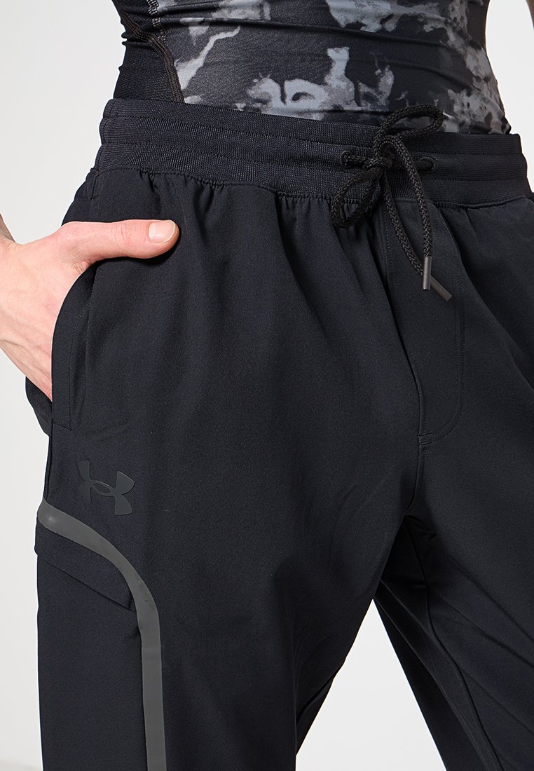 Pantalones deportivos negros hechos de una tela ligera, con una cintura elástica, bolsillos laterales y un logo sutil en el muslo izquierdo.