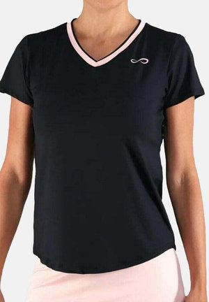 Mujer con una camiseta negra de manga corta y escote en V, con ribetes rosas y un pequeño símbolo de infinito blanco en el lado izquierdo del pecho.