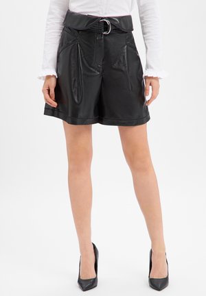 Czarne szorty ze sztucznej skóry z szerokim pasem, szlufkami na pasek i srebrną klamrą. Posiadają przednie kieszenie i gładką fakturę.