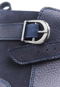 Zapato de cuero azul marino con un acabado texturizado, herrajes de hebilla plateados y costuras azules contrastantes en material de tela suave.