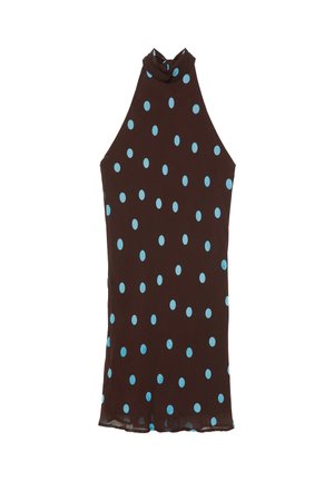 Frau trägt ein schwarzes Neckholderkleid mit blauen Polka-Dots, mit tiefem Rückenausschnitt und einer gebundenen Schleife am Hals.