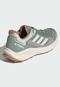 Chaussure de sport verte et grise avec une tige en maille, un col rembourré, trois bandes blanches et des accents rose clair sur le talon et la semelle.