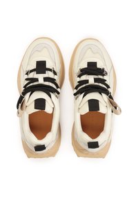 Masywne sneakersy w kremowej i beżowej skórze z czarnymi sznurowadłami, teksturowanymi akcentami oraz brązową gumową podeszwą. Posiadają pętelkę na pięcie.