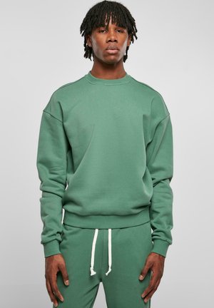 Grüner Sweatshirt mit Rundhalsausschnitt, gerippten Bündchen und Saum. Weicher, strukturierter Stoff. Kombiniert mit passenden Jogginghosen, die weiße Kordeln haben.