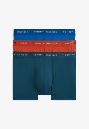 Drie paar boxershorts in blauw, roestkleur en donkerteal, elk met een merkband met de tekst "Tommy Hilfiger" en het logo.