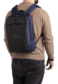 Zaino nero e blu con più scomparti con cerniere, schienale imbottito, spallacci regolabili e un logo sul davanti. Tessuto resistente.