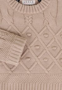 Beige gebreide trui met een gestructureerd diamanten patroon, geribbelde manchetten en een ronde halslijn met een label zichtbaar aan de binnenkant van de kraag.
