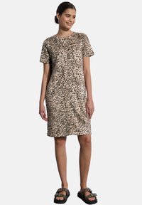 Leopardenmuster T-Shirt-Kleid in Braun und Schwarz, mit lockerer Passform, kurzen Ärmeln und knielangem Saum. Kombiniert mit schwarzen Riemchensandalen.