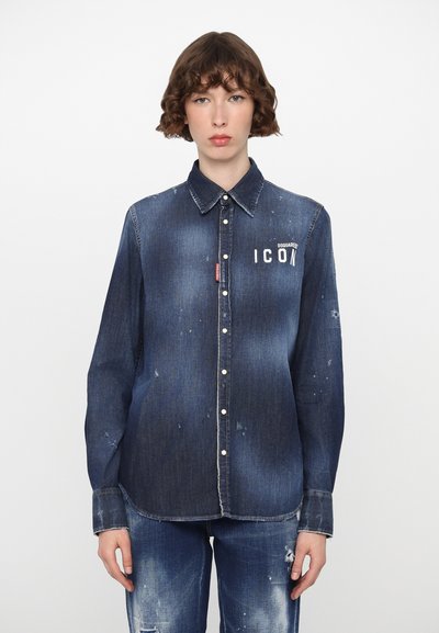 Camisa de denim en azul oscuro con efecto desgastado, diseño de botones y texto "ICON" en el lado izquierdo del pecho. Presenta un ligero desgaste y costuras blancas.