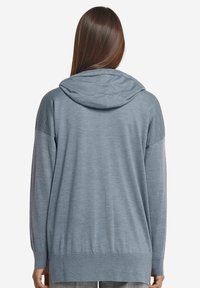 Ljusblå huvtröja med långa ärmar, tillverkad av mjukt tyg, med ribbad nederkant och texturerade paneldetaljer på axlarna.