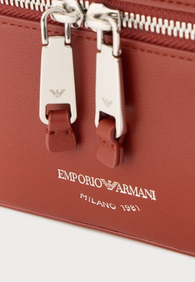 Καφέ δερμάτινη τσάντα Emporio Armani με ασημένιες φερμουάρ και λογότυπο χαραγμένο κάτω από δύο τσόπες φερμουάρ, με ημερομηνία Μιλάνο 1981.
