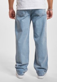 Vaqueros de denim azul claro con un corte relajado, que presentan una textura sutil, diseño de cinco bolsillos y detalles cosidos en los bolsillos traseros.