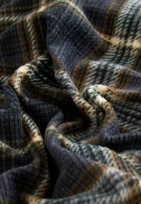 Gewebter Karostoff in Marineblau, Beige und Dunkelgrün, mit einer weichen, strukturierten Oberfläche, die abwechselnde Streifen und ein gemütliches Aussehen aufweist.