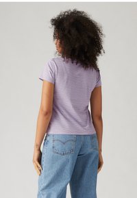 Purple and white striped short-sleeve T-shirt, fitted design, cotton fabric, paired with high-waisted light blue jeans.