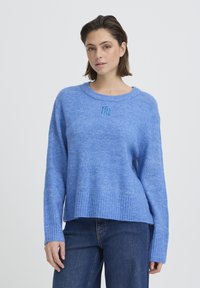 Pull bleu clair en matière douce, avec un ourlet et des poignets côtelés, orné d'un petit logo brodé sur le devant.