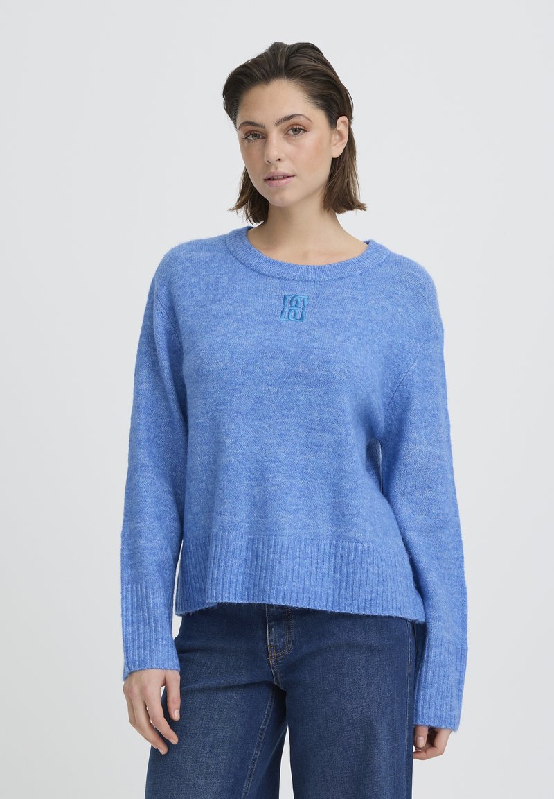 Pull bleu clair en matière douce, avec un ourlet et des poignets côtelés, orné d'un petit logo brodé sur le devant.