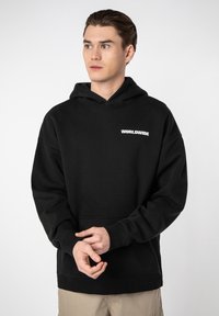 Black hoodie with a kangaroo pocket, made of soft material. Features "WORLDWIDE" logo in white on chest; relaxed fit and adjustable hood.