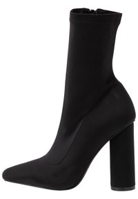 Bottes noires à la cheville avec un bout pointu, fabriquées en tissu lisse. Elles disposent d'un talon épais et haut ainsi que d'un design sans lacets avec des détails de couture minimaux.