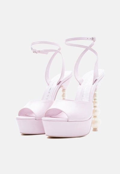 Lilla platformsandaler med åbne tæer, ankelstropper og skulpturelle perle-lignende høje hæle på en hvid baggrund.